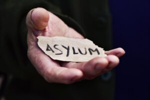 closeup of the hand of an old man with a piece of paper with the word asylum