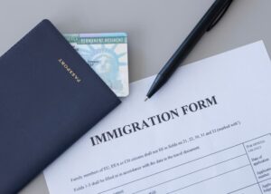 United States passport, permanent resident (green) card and immigration form on desk.